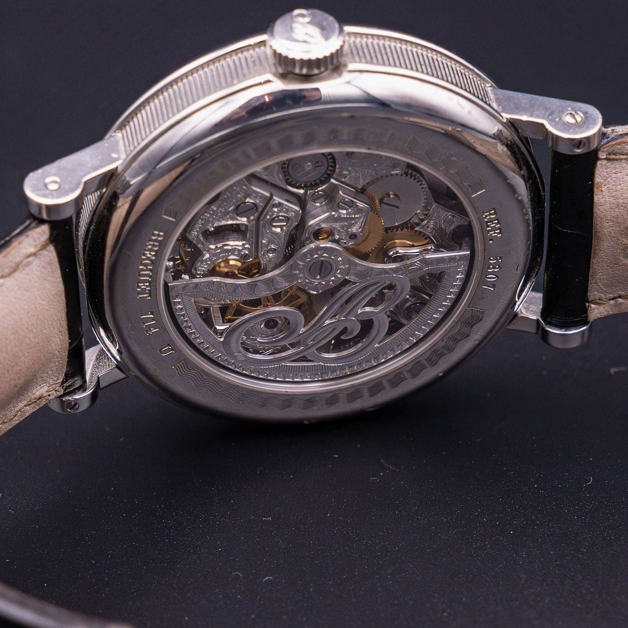 Close-up of a mechanical wristwatch with a visible brand name on a dark background